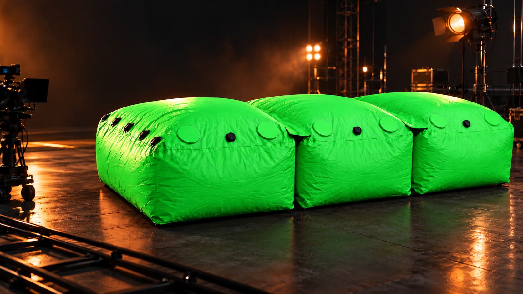 Three connected modular stunt bags in vivid chroma-key green on a film soundstage