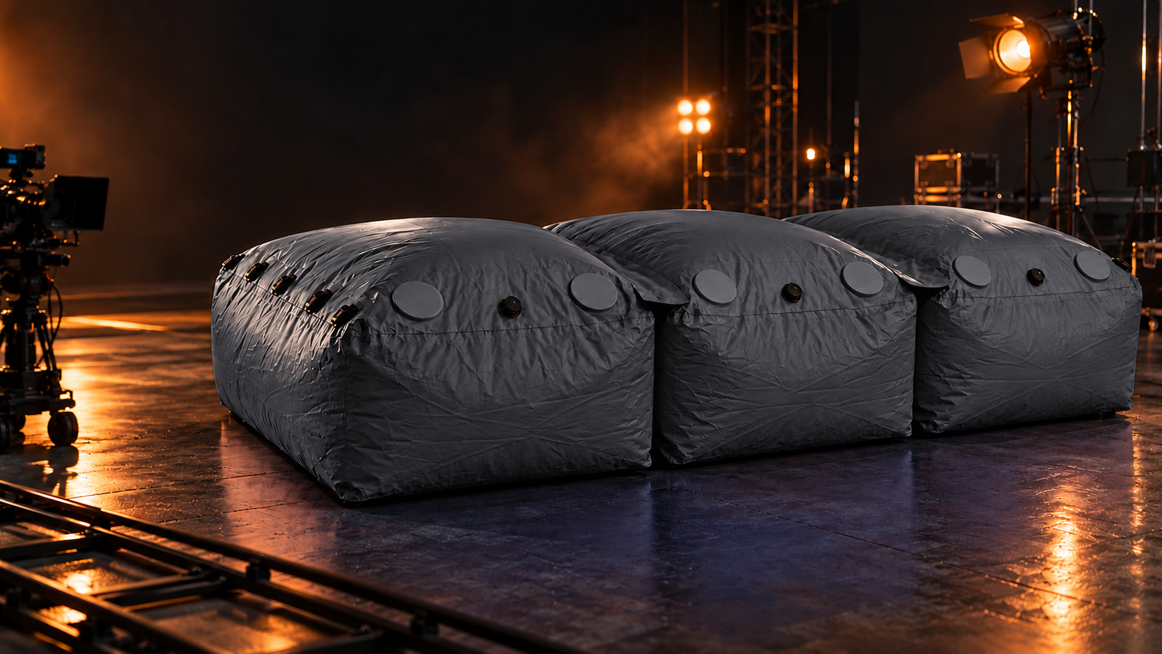 Three connected modular stunt bags in dark gray on a film soundstage